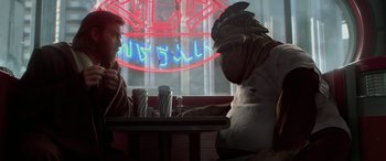 Movie still from “Star Wars: Episode II - Attack of the Clones” (2002), directed by George Lucas – Two people sitting at a table in front of a neon sign; Medium shot, Over the shoulder angle
