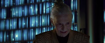Movie still from “Star Wars: Episode II - Attack of the Clones” (2002), directed by George Lucas – An older woman with a hair piece in front of a building; Close Up shot, Over the shoulder angle