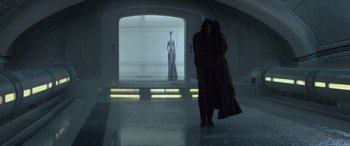 Movie still from “Star Wars: Episode II - Attack of the Clones” (2002), directed by George Lucas – A woman in a long black coat standing next to a mannequin; Wide shot, Low angle