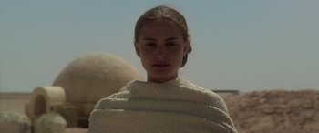Movie still from “Star Wars: Episode II - Attack of the Clones” (2002), directed by George Lucas – A young woman wrapped in a blanket looks at the camera; Close Up shot, Low angle