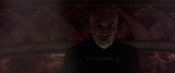 Movie still from “Star Wars: Episode II - Attack of the Clones” (2002), directed by George Lucas – An old man with a beard and a chain around his neck; Close Up shot, Over the shoulder angle
