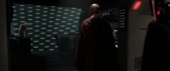 Movie still from “Star Wars: Episode II - Attack of the Clones” (2002), directed by George Lucas – A bald man in a red robe standing in a dark room; Medium shot, Over the shoulder angle