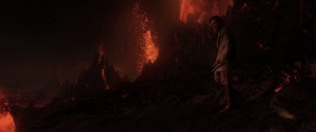 Movie still from “Star Wars: Episode III - Revenge of the Sith” (2005), directed by George Lucas – A man standing on top of a hill next to a fire; Wide shot, Over the shoulder angle