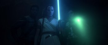 Movie still from “Star Wars: Episode IX - The Rise of Skywalker” (2019), directed by J.J. Abrams – A woman holding a light saber while standing next to two men; Medium shot, Low angle