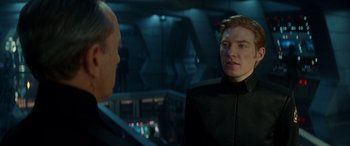 Movie still from “Star Wars: Episode IX - The Rise of Skywalker” (2019), directed by J.J. Abrams – A man in a black suit talking to another man in a black suit; Close Up shot, Over the shoulder angle