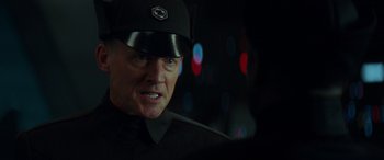 Movie still from “Star Wars: Episode IX - The Rise of Skywalker” (2019), directed by J.J. Abrams – A man wearing a black uniform and a black hat; Close Up shot, Over the shoulder angle