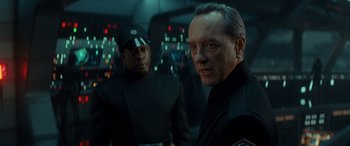 Movie still from “Star Wars: Episode IX - The Rise of Skywalker” (2019), directed by J.J. Abrams – A man in a black suit standing next to another man in a black suit; Close Up shot, Over the shoulder angle