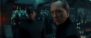 Movie still from “Star Wars: Episode IX - The Rise of Skywalker” (2019), directed by J.J. Abrams – A man in a black suit standing next to another man in a black suit; Close Up shot, Over the shoulder angle