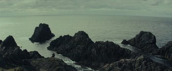 Movie still from “Star Wars: Episode VIII - The Last Jedi” (2017), directed by Rian Johnson – A person sitting on top of a rock near the ocean; Extreme Wide shot, High angle