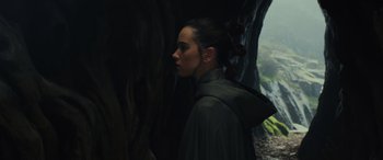 Movie still from “Star Wars: Episode VIII - The Last Jedi” (2017), directed by Rian Johnson – A woman in a hooded jacket standing next to a tree; Close Up shot, Over the shoulder angle