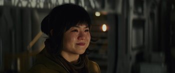 Movie still from “Star Wars: Episode VIII - The Last Jedi” (2017), directed by Rian Johnson – A young woman is smiling for the camera; Close Up shot, Over the shoulder angle