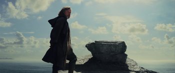 Movie still from “Star Wars: Episode VIII - The Last Jedi” (2017), directed by Rian Johnson – A man walking on a rocky cliff with a sky in the background; Medium shot, Low angle