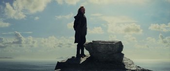 Movie still from “Star Wars: Episode VIII - The Last Jedi” (2017), directed by Rian Johnson – A man standing on top of a rock near the ocean; Wide shot, Low angle