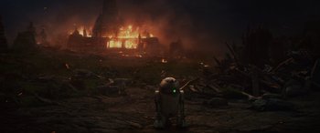 Movie still from “Star Wars: Episode VIII - The Last Jedi” (2017), directed by Rian Johnson – An r 2 d 2 robot standing in front of a burning building; Extreme Wide shot, Low angle