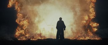 Movie still from “Star Wars: Episode VIII - The Last Jedi” (2017), directed by Rian Johnson – A man standing in front of a fire and smoke; Extreme Wide shot, Low angle