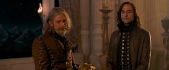 Movie still from “Stardust” (2007), directed by Matthew Vaughn – A man with long hair standing next to another man; Medium shot, Over the shoulder angle