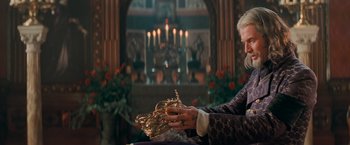 Movie still from “Stardust” (2007), directed by Matthew Vaughn – A person holding a crown in a room with candles in the background; Medium shot, Over the shoulder angle