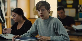 Movie still from “Stargirl” (2020), directed by Julia Hart – A young man sitting at a table in front of other people; Medium shot, Over the shoulder angle