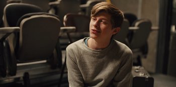 Movie still from “Stargirl” (2020), directed by Julia Hart – A young man sitting in front of a row of chairs; Close Up shot, Over the shoulder angle