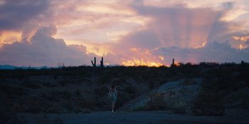 Movie still from “Stargirl” (2020), directed by Julia Hart – A woman standing on a dirt road at sunset; Extreme Wide shot, Low angle