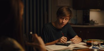 Movie still from “Stargirl” (2020), directed by Julia Hart – A young man sitting at a table doing homework; Medium shot, Over the shoulder angle