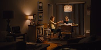 Movie still from “Stargirl” (2020), directed by Julia Hart – Two people sitting at a table in a living room; Wide shot, Over the shoulder angle