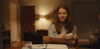 Movie still from “Stargirl” (2020), directed by Julia Hart – A woman sitting at a table with a book in her hands; Medium shot, Over the shoulder angle