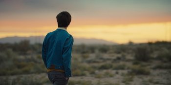 Movie still from “Stargirl” (2020), directed by Julia Hart – A man standing in a field looking at the sky; Medium shot, Over the shoulder angle