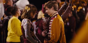 Movie still from “Stargirl” (2020), directed by Julia Hart – A couple of people that are standing up together; Medium shot, Over the shoulder angle