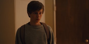 Movie still from “Stargirl” (2020), directed by Julia Hart – A young man wearing a gray shirt and a brown backpack; Medium shot, Over the shoulder angle