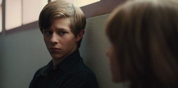 Movie still from “Stargirl” (2020), directed by Julia Hart – A young man looking into a mirror while standing next to a wall; Close Up shot, Over the shoulder angle