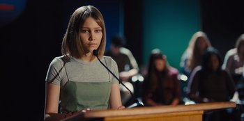 Movie still from “Stargirl” (2020), directed by Julia Hart – A woman standing at a podium speaking to a crowd; Medium shot, Over the shoulder angle