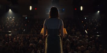 Movie still from “Stargirl” (2020), directed by Julia Hart – A woman standing in front of an audience at a public event; Medium shot, Low angle