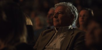Movie still from “Stargirl” (2020), directed by Julia Hart – An older man sitting in front of an audience; Close Up shot, Low angle