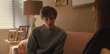 Movie still from “Stargirl” (2020), directed by Julia Hart – A young man sitting on top of a pink couch; Medium shot, Over the shoulder angle