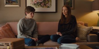 Movie still from “Stargirl” (2020), directed by Julia Hart – A woman and a boy sitting on a pink couch; Medium shot, Over the shoulder angle