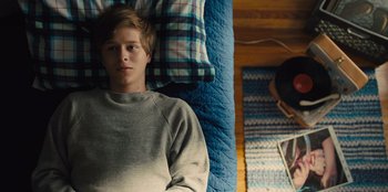 Movie still from “Stargirl” (2020), directed by Julia Hart – A man laying in a bed with a blanket on top of him; Medium shot, Overhead angle