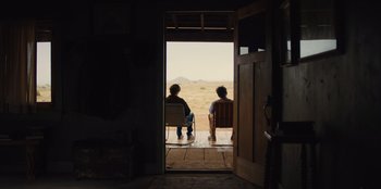 Movie still from “Stargirl” (2020), directed by Julia Hart – Two people sitting in chairs looking out a window; Wide shot, Over the shoulder angle