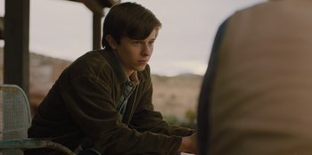 Movie still from “Stargirl” (2020), directed by Julia Hart – A young man sitting in front of another man; Medium shot, Over the shoulder angle
