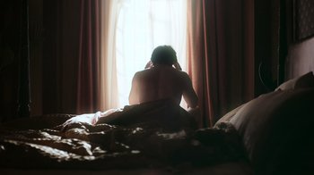 Movie still from “Still: A Michael J. Fox Movie” (2023), directed by Davis Guggenheim – A woman sitting on a bed in front of a window; Medium shot, Low angle