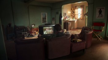Movie still from “Still: A Michael J. Fox Movie” (2023), directed by Davis Guggenheim – A woman sitting on a couch watching television; Wide shot, High angle
