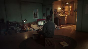 Movie still from “Still: A Michael J. Fox Movie” (2023), directed by Davis Guggenheim – A man sitting on the floor in front of a television; Wide shot, High angle