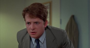 Movie still from “Still: A Michael J. Fox Movie” (2023), directed by Davis Guggenheim – A man in a suit and tie sitting in a room; Close Up shot, Over the shoulder angle