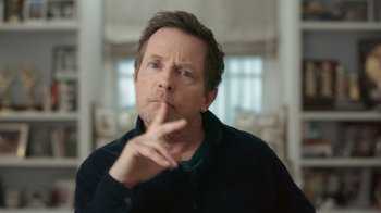 Movie still from “Still: A Michael J. Fox Movie” (2023), directed by Davis Guggenheim – A person holding his finger to his mouth; Close Up shot, Over the shoulder angle