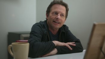 Movie still from “Still: A Michael J. Fox Movie” (2023), directed by Davis Guggenheim – A person sitting at a table; Close Up shot, Over the shoulder angle