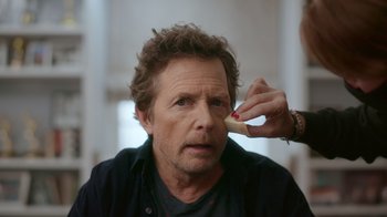 Movie still from “Still: A Michael J. Fox Movie” (2023), directed by Davis Guggenheim – A man is looking at the camera while a woman is holding a piece of wood; Close Up shot, Over the shoulder angle