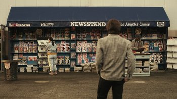 Movie still from “Still: A Michael J. Fox Movie” (2023), directed by Davis Guggenheim – A man and a woman standing in front of a newsstand; Wide shot, Over the shoulder angle