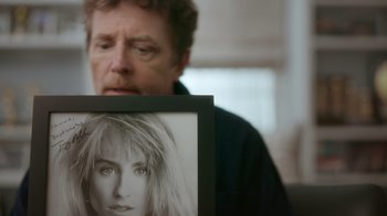 Movie still from “Still: A Michael J. Fox Movie” (2023), directed by Davis Guggenheim – A man looking at a picture of a woman's face; Extreme Close Up shot, Over the shoulder angle