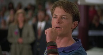 Movie still from “Still: A Michael J. Fox Movie” (2023), directed by Davis Guggenheim – A man with his hand on his chin in front of a group of people; Close Up shot, Low angle