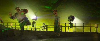 Movie still from “Strange World” (2022), directed by Don Hall – A man standing on some steps in front of a green light; Wide shot, Low angle